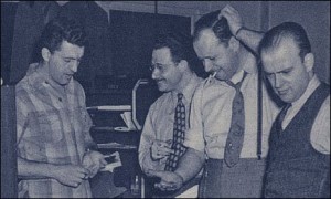 Marty Taras at Famous Studios in a 1945 photograph, with cigarette and hand on his head. (with George Ottioni, Lou Zukor and Pete DeAngel)